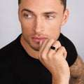 Man wearing the Anthem Onyx Octagon Ring, featuring an onyx gemstone with sterling silver caviar beading, thoughtfully posed with his hand.