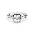 A silver ring featuring a cushion-cut white topaz gemstone in a bezel setting, surrounded by a halo of small round beads and a textured beaded band.