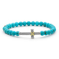 Turquoise beaded bracelet with a silver and gold cross charm on a white background