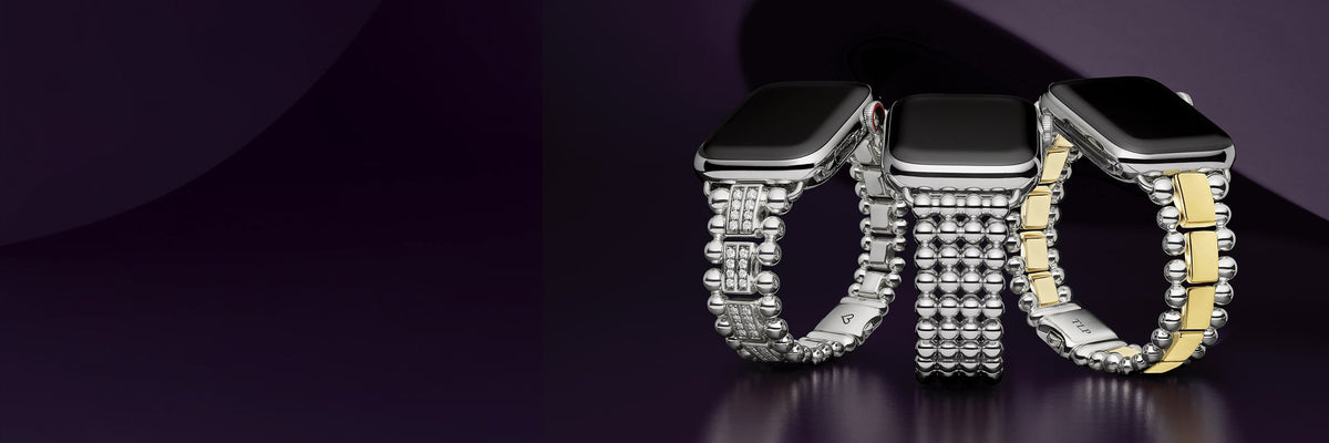 Three smartwatches with metallic beaded bands displayed side by side on a dark purple reflective surface. The left and center watches have silver bands, and the right watch has a two-tone silver and gold band.
