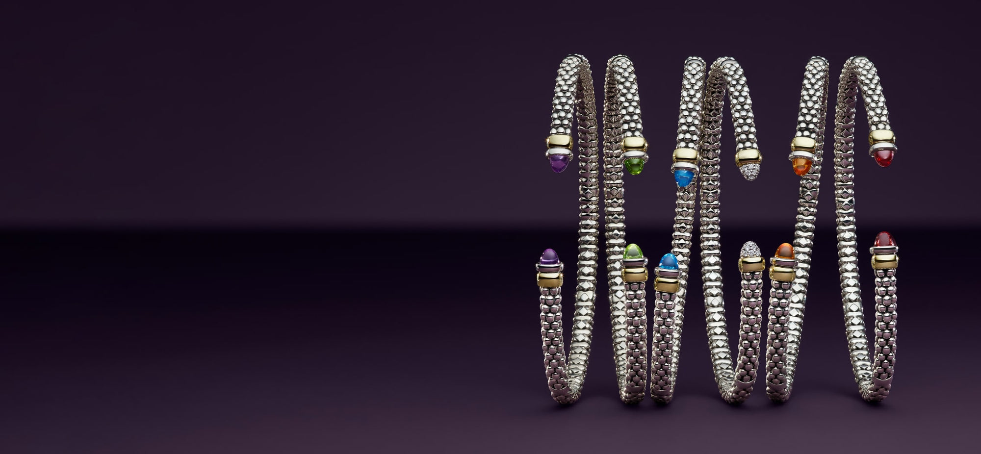 Set of silver cuff bracelets with gemstone accents on a dark background