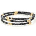 Ten small 18k gold stations highlighted by black ceramic Caviar beading form this coil bracelet finished with an 18k gold endcaps.