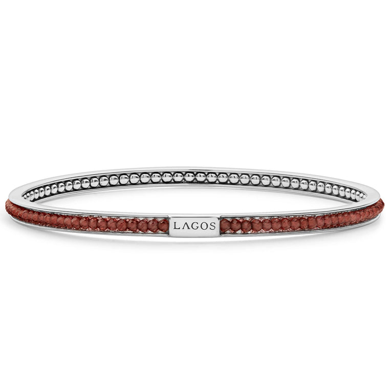 Garnet gemstones set with smoothly polished sterling silver forms this round bangle detailing the LAGOS logo.