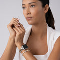 Woman wearing the Smart Caviar 18K Gold Gift Set, featuring a smartwatch band and coordinating bracelet with signature Caviar beading, embodying stylish elegance.