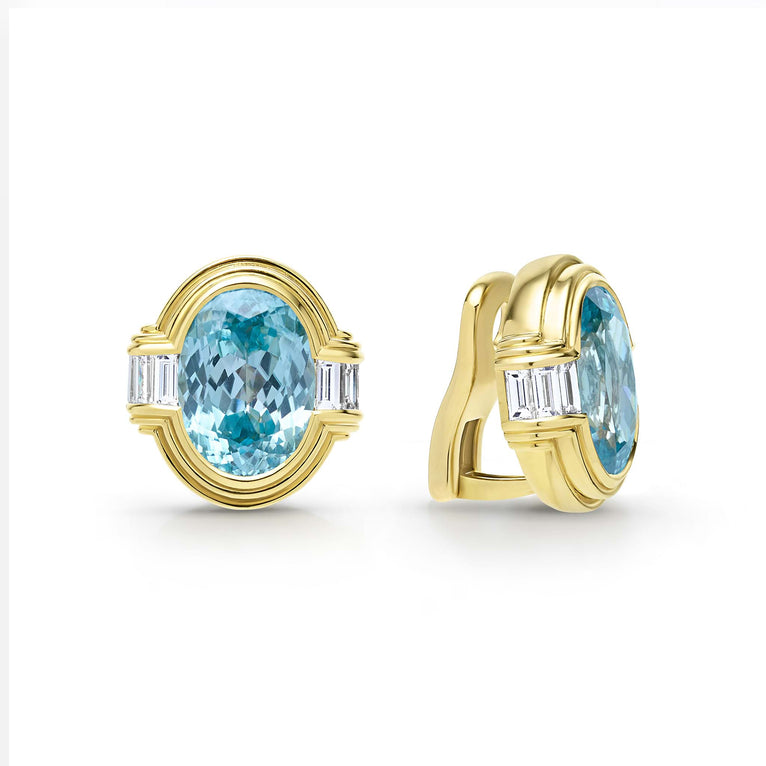 Smooth 18k gold and blue zircon gemstone accented by emerald cut diamonds form these oval shaped omega clip earrings. LAGOS diamonds are the highest quality natural stones.