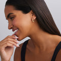 Woman wearing gold hoop earrings with a neutral background