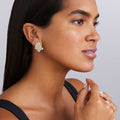 woman wearing cluster diamond set in 18K gold statement earrings white background