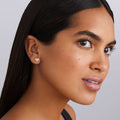 woman wearing five bezel-cut diamond stud earrings set in 18K gold on a white background
