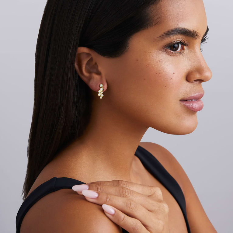 Woman wearing seven diamond drop earrings set in gold with friction back on a white background