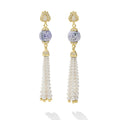 Pair of earrings with gold accents, purple gemstones, and pearl tassels on a white background