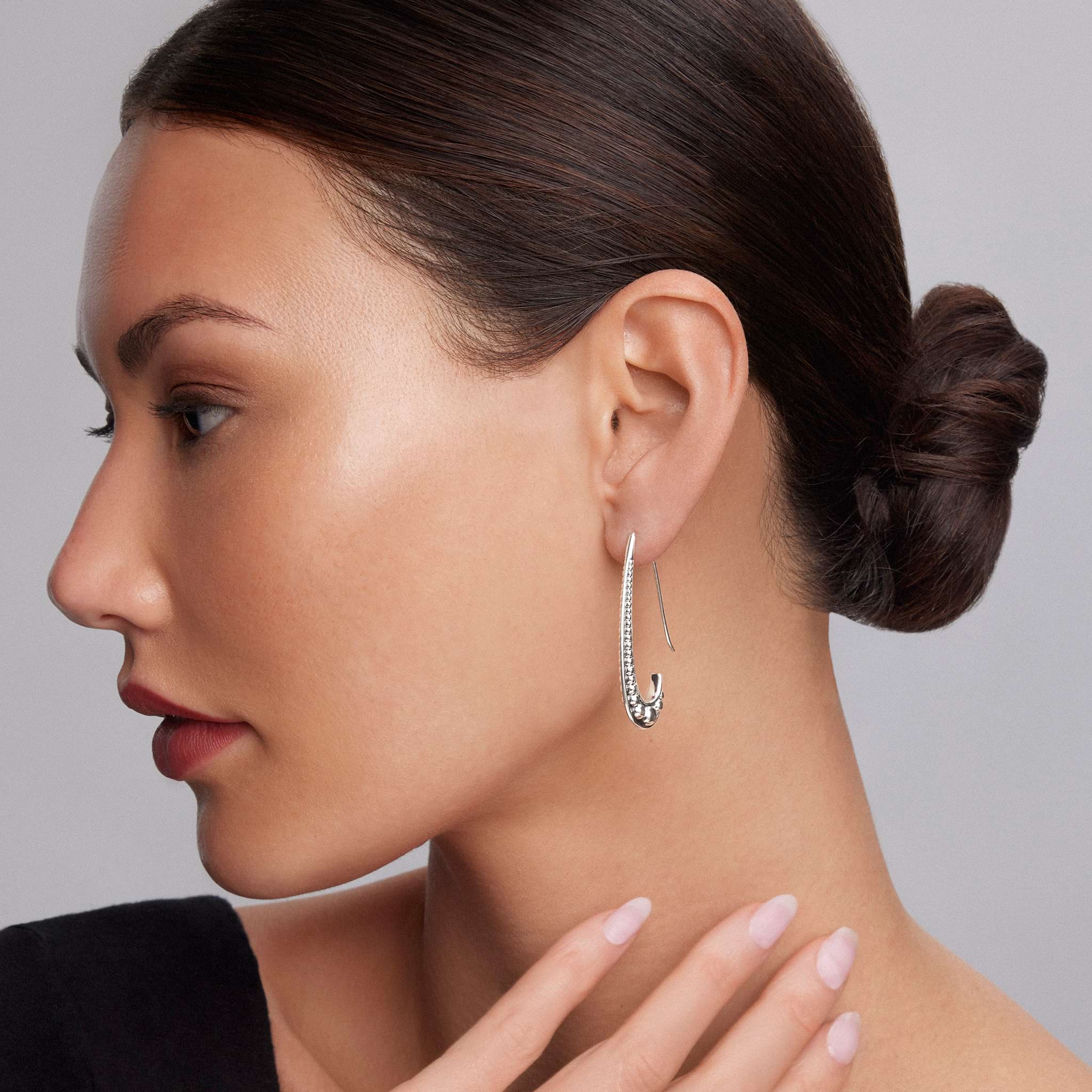 Profile of a woman wearing Signature Caviar Smooth Hook Drop Earrings in sterling silver, featuring polished beading and a sleek design, capturing LAGOS elegance.