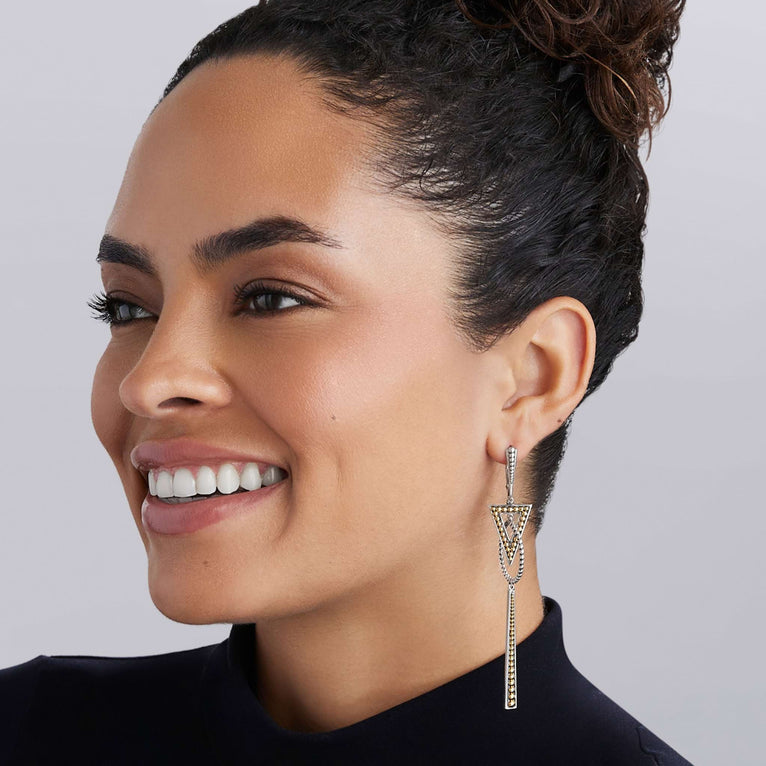 Smiling person showcases Signature Caviar Two-Tone Triangle Circle Drop Earrings, featuring intricate gold and silver triangular motifs with fine chain details.