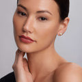 Woman wearing KSL Small Caviar Pyramid Stud Earrings in 18k gold with sterling silver accents, highlighting her well-groomed features against a light-gray background.