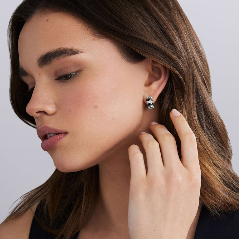 woman wearing side of sterling silver beaded huggie earrings with black ceramic and diamond details