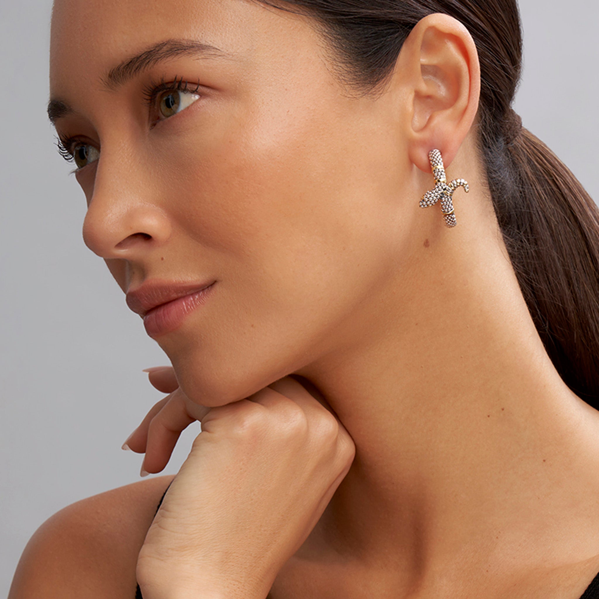 Profile view of a woman showcasing Rare Wonders Two-Tone Snake Hoop Earrings, featuring sterling silver caviar beading with 18K gold accents, reflecting LAGOS's craftsmanship.