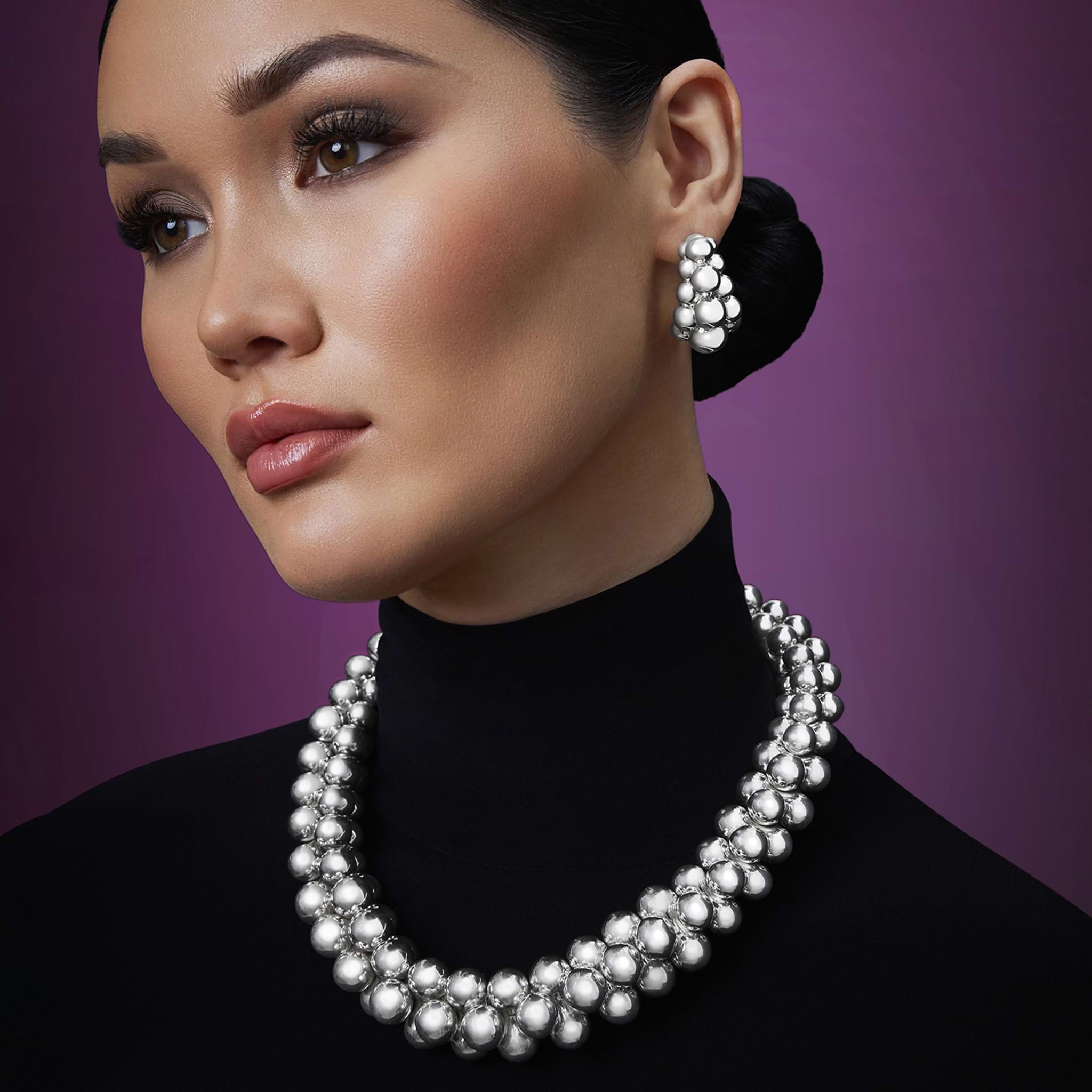 woman wearing three-row beaded sterling silver statement hoop earrings and silver beaded statement necklace