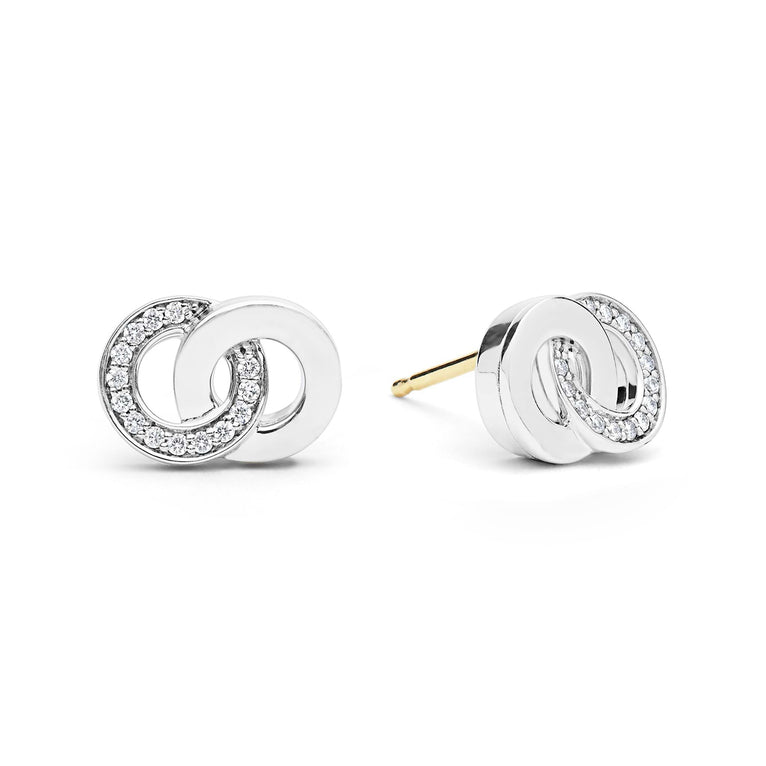 Signature Caviar Silver Interlocking Diamond Stud Earrings feature white metal loops with pavé diamonds and 14K gold posts, showcasing elegant craftsmanship and timeless design.