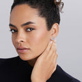 Young woman wearing Signature Caviar Silver Interlocking Diamond Stud Earring, showcasing the elegant design with shimmering diamonds set in sterling silver.