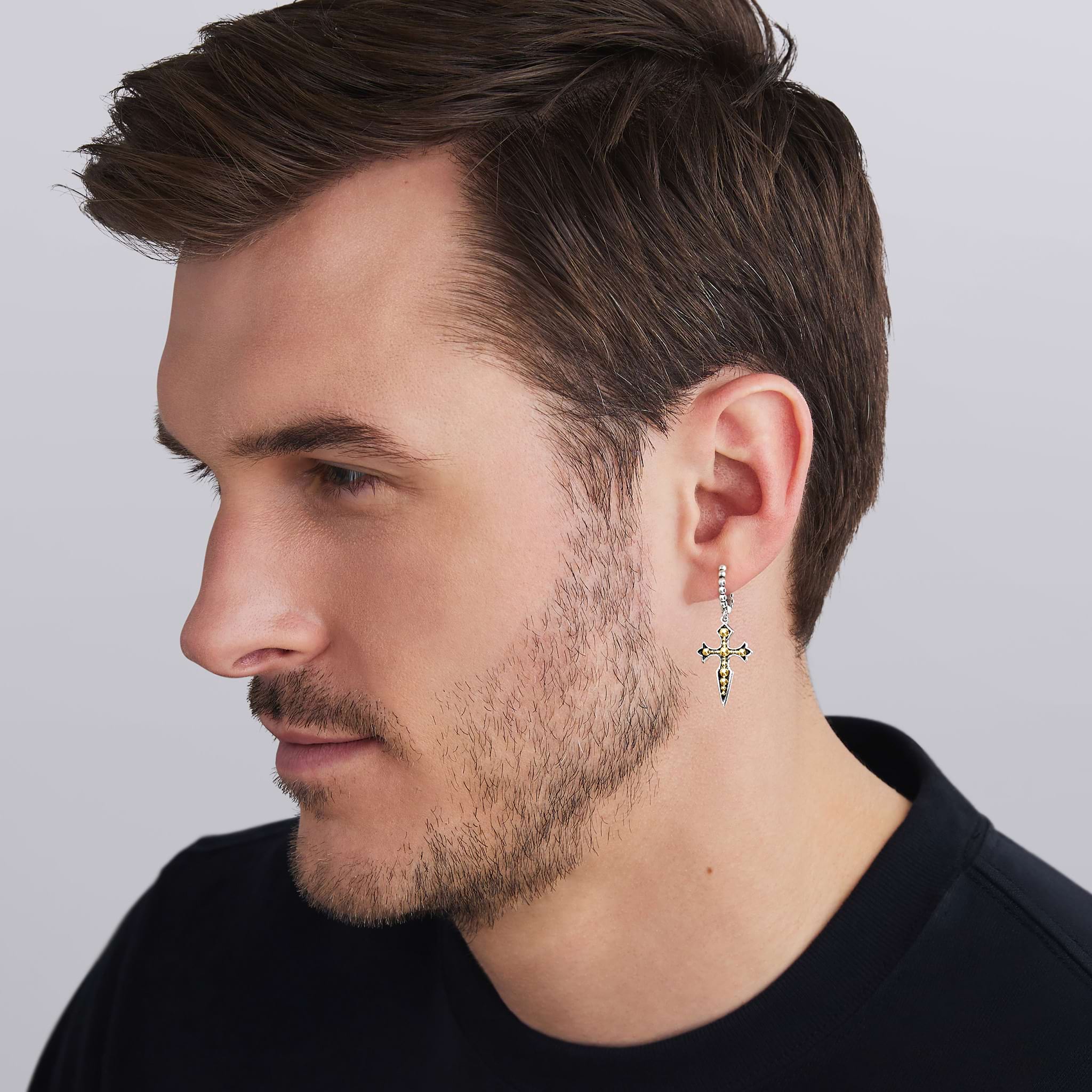 man wearing two-tone beaded drop hoop earring with gold and silver cross dangle