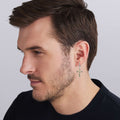 man wearing two-tone beaded drop hoop earring with gold and silver cross dangle