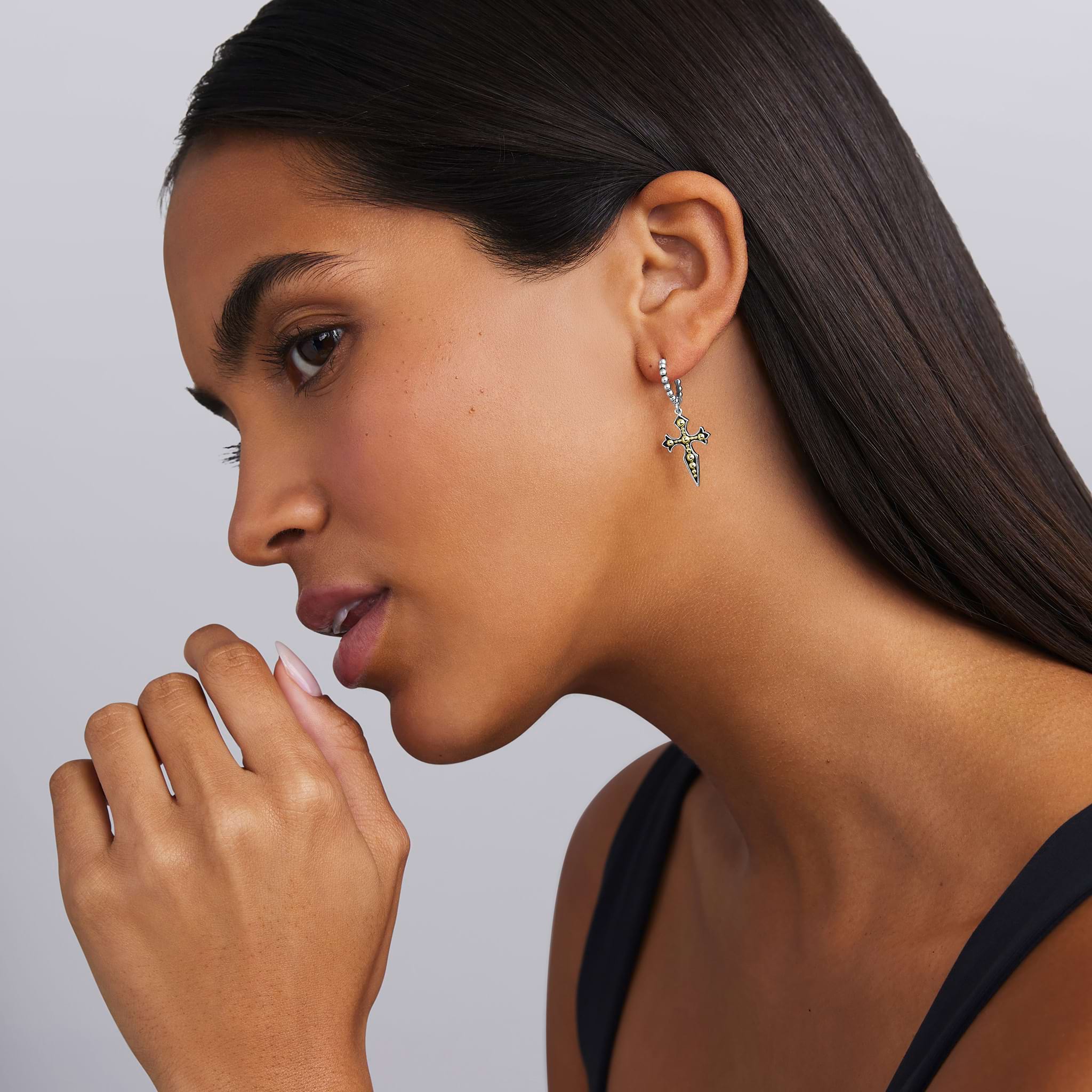 woman wearing two-tone beaded drop hoop earring with gold and silver cross dangle