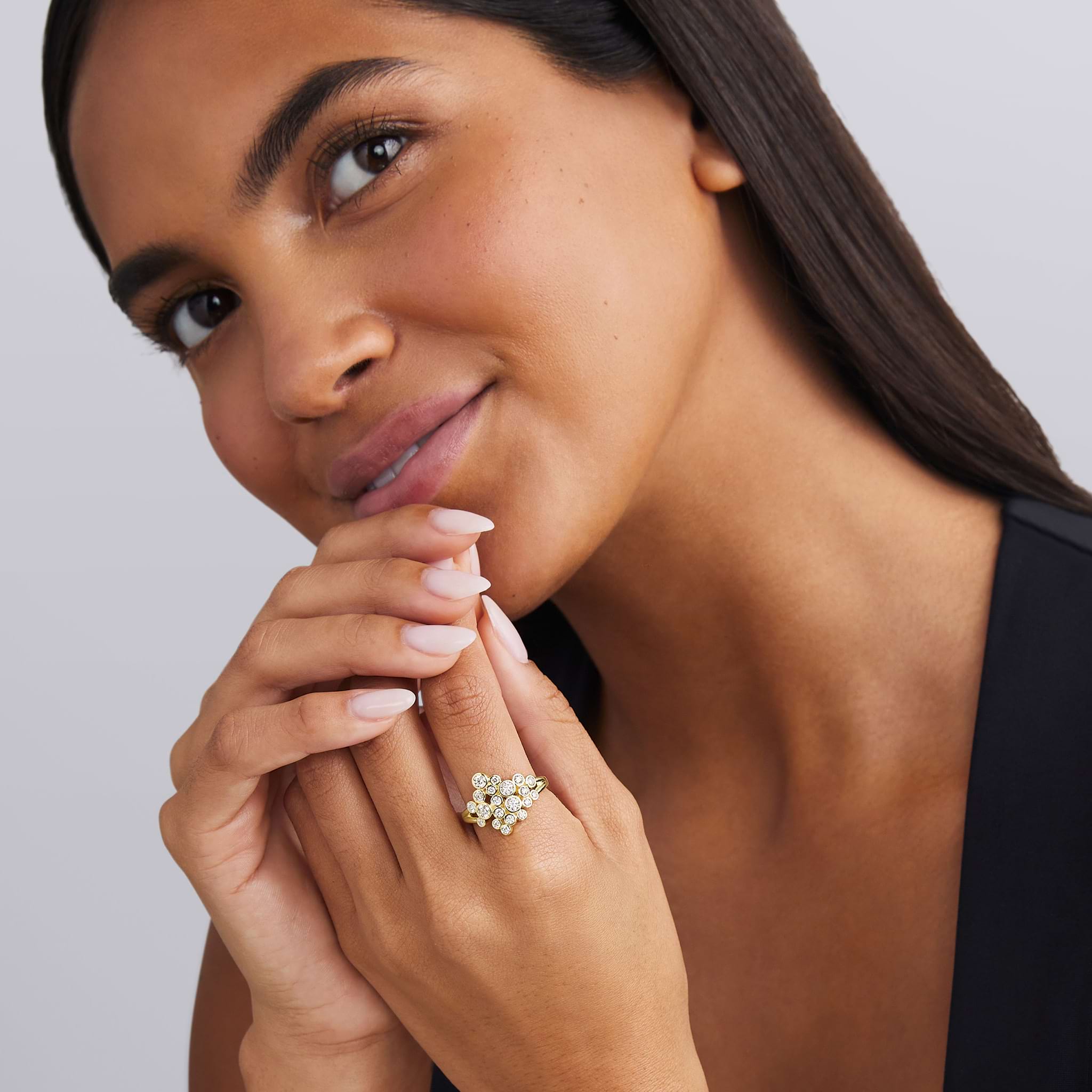 woman wearing bezel-cut diamond cluster statement ring set in 18K gold on white background