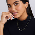 Woman wearing nineteen bezel-cut diamond horizonal pendant on a 18K gold beaded chain with white background