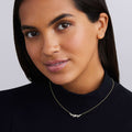 woman wearing nine bezel-cut diamond horizonal pendant on a 18K gold beaded chain