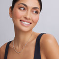 Young woman wearing a Caviar Icon Silver Caviar Beaded Necklace with fluted accents, smiling and looking aside, highlighting the necklace's elegant craftsmanship against her collarbone.