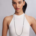 Woman wearing a Caviar Icon Onyx Necklace with black beaded design and fluted accents, elegantly draped over a high-neck white top.
