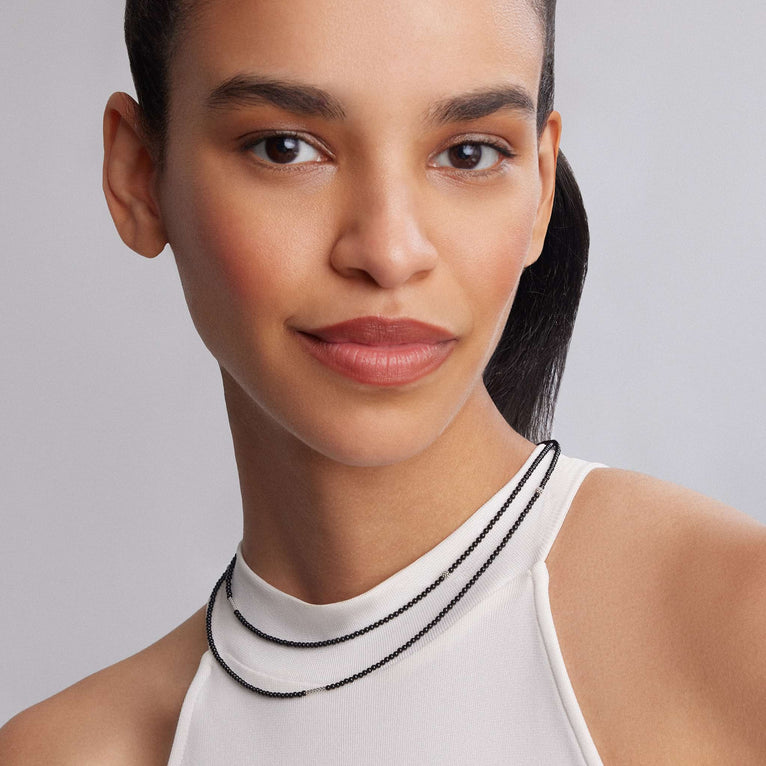 Caviar Icon Onyx Necklace on model, featuring three black beaded strands with natural onyx gemstones and caviar beading, elegantly draped around the neck.