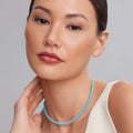 Close-up of a woman wearing the Blue Caviar Silver Station Ceramic Beaded Necklace, featuring blue beads and sterling silver caviar beading.