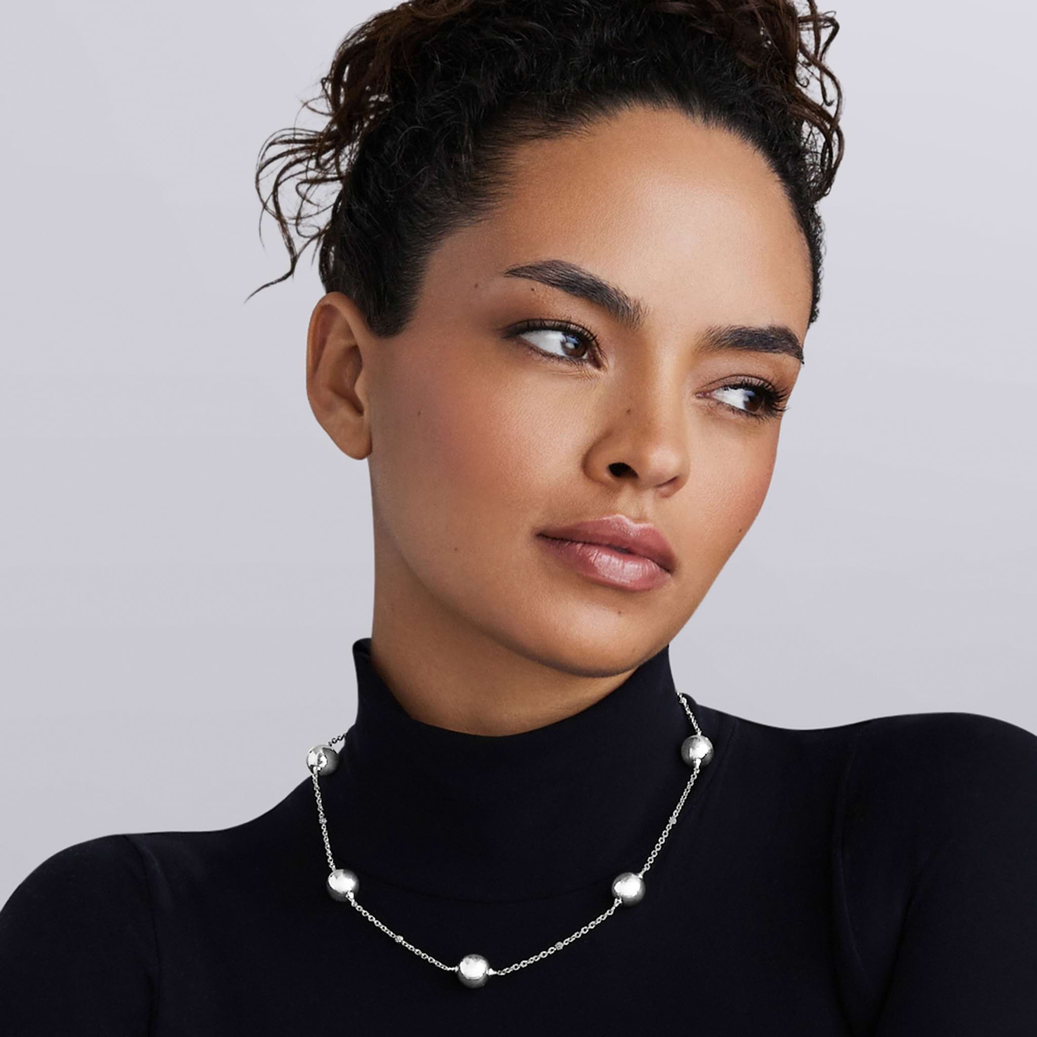 Caviar Bubbly Silver Beaded Station Necklace in sterling silver drapes elegantly on a woman, showcasing its polished bubble-shaped stations for a refined LAGOS elegance.