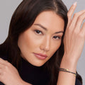 Woman wearing Black Caviar Ceramic Wrap Bracelet with gold accents, showcasing its sleek design against her smooth skin and manicured nails.