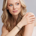 Young woman wearing a Black Caviar Ceramic Wrap Diamond Bracelet with gold-tone end caps, showcasing LAGOS elegant craftsmanship.