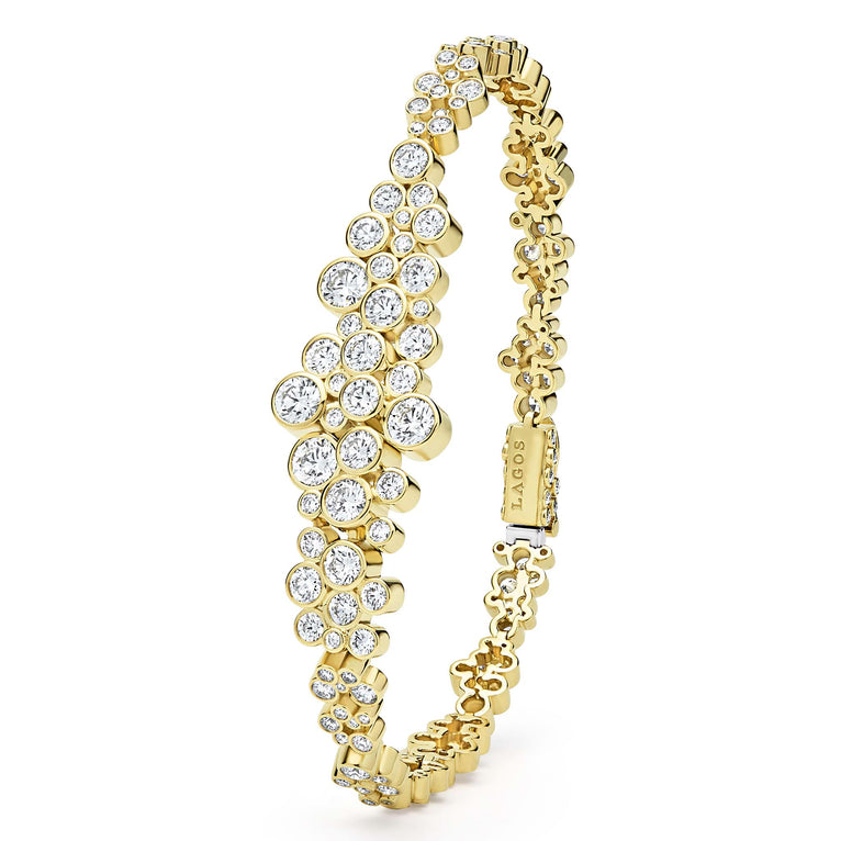 upright view of cluster diamond tennis bracelet set in 18K gold with LAGOS engraving on white background