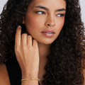  3mm, gently touches her cheek, showcasing the bracelet’s sleek, beaded design against her smooth complexion.