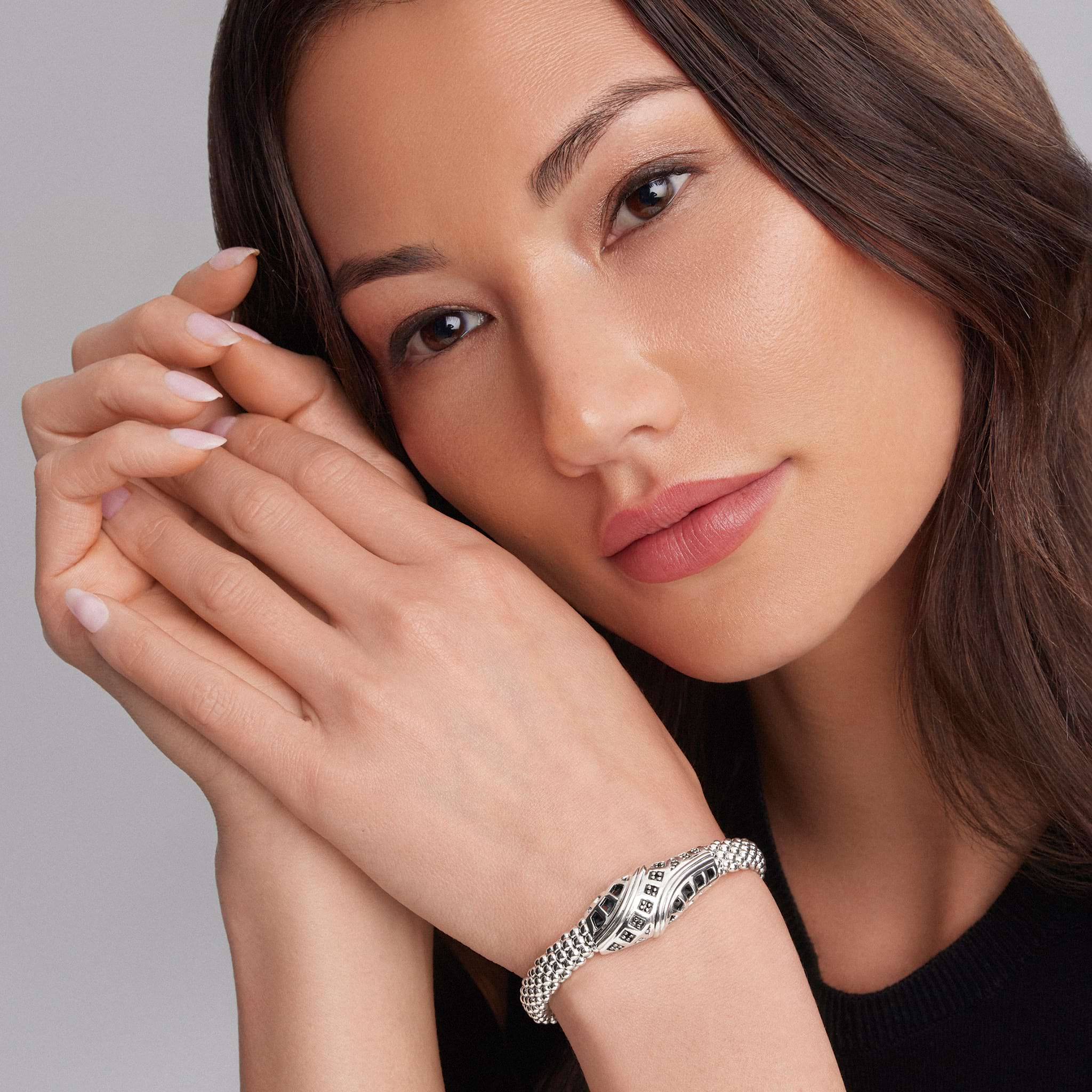 Woman's face with pale-pink nails frames her face, highlighting the Keep Memory Alive Caviar Beaded Bracelet, a chunky silver piece with a chain-mail design.