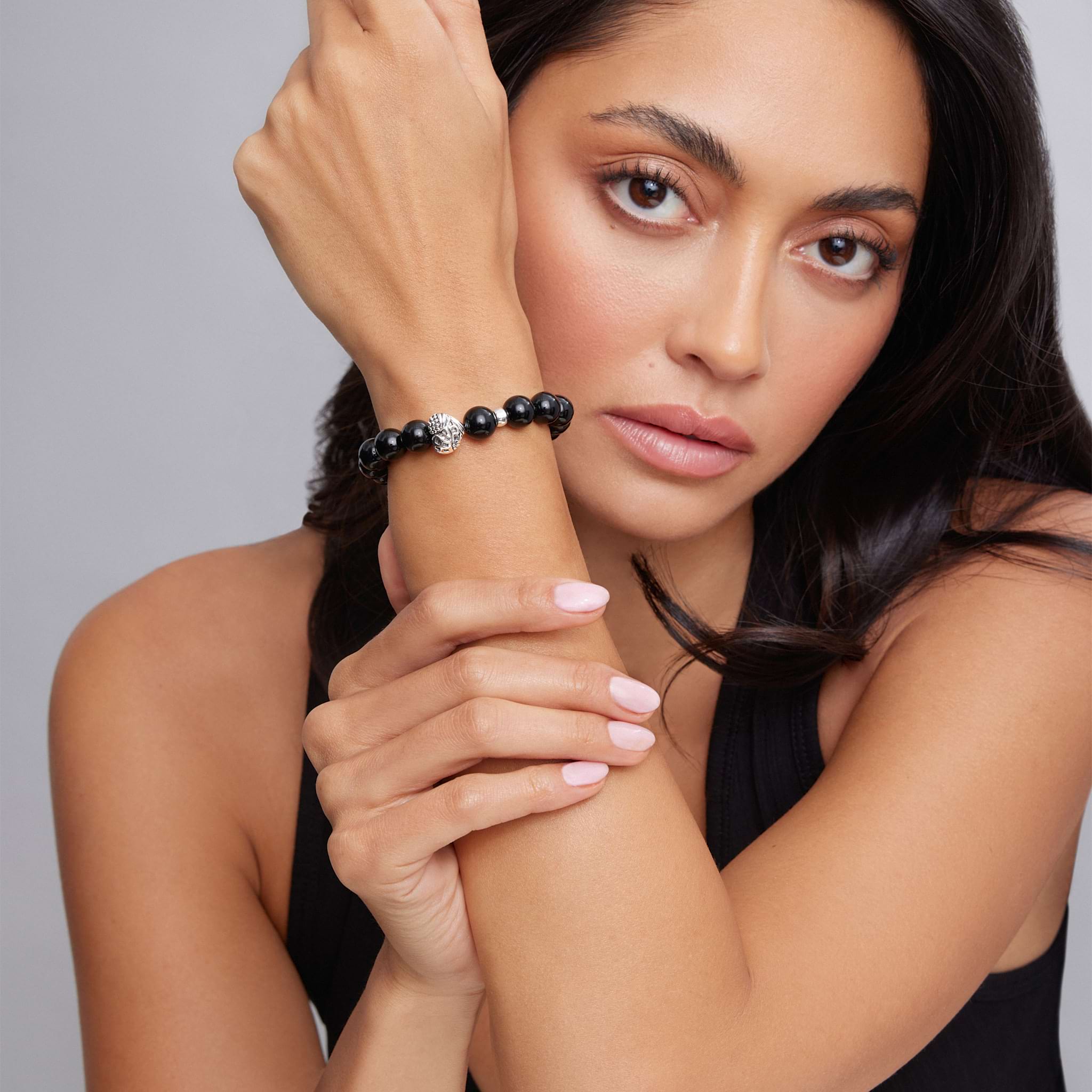 Young woman showcases the Keep Memory Alive Black Agate Silver Station Bead Bracelet, featuring glossy black beads and a central decorative silver bead.