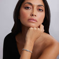 Woman resting chin on hand, showcasing the Signature Caviar XOXO Stretch Bead Bracelet in sterling silver, featuring an engraved XOXO plate and polished stretch beads.