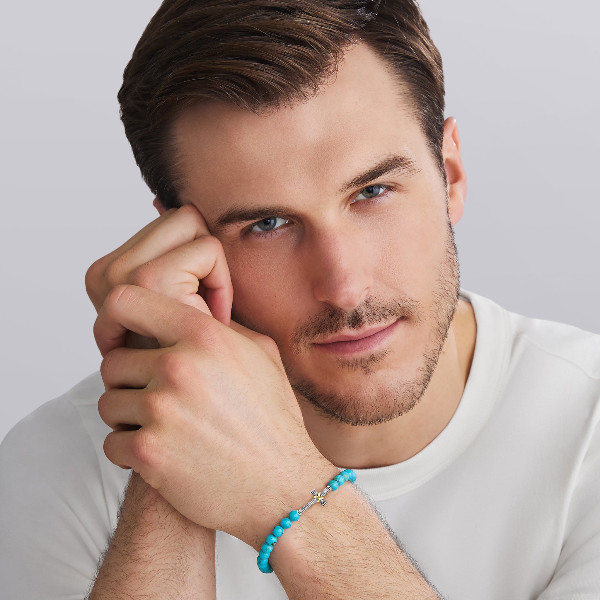 Man wearing a turquoise bracelet on a plain background