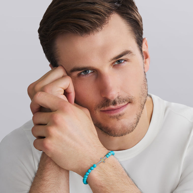Man wearing a turquoise bracelet on a plain background