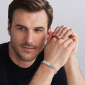 Man wearing a silver bracelet on a plain background