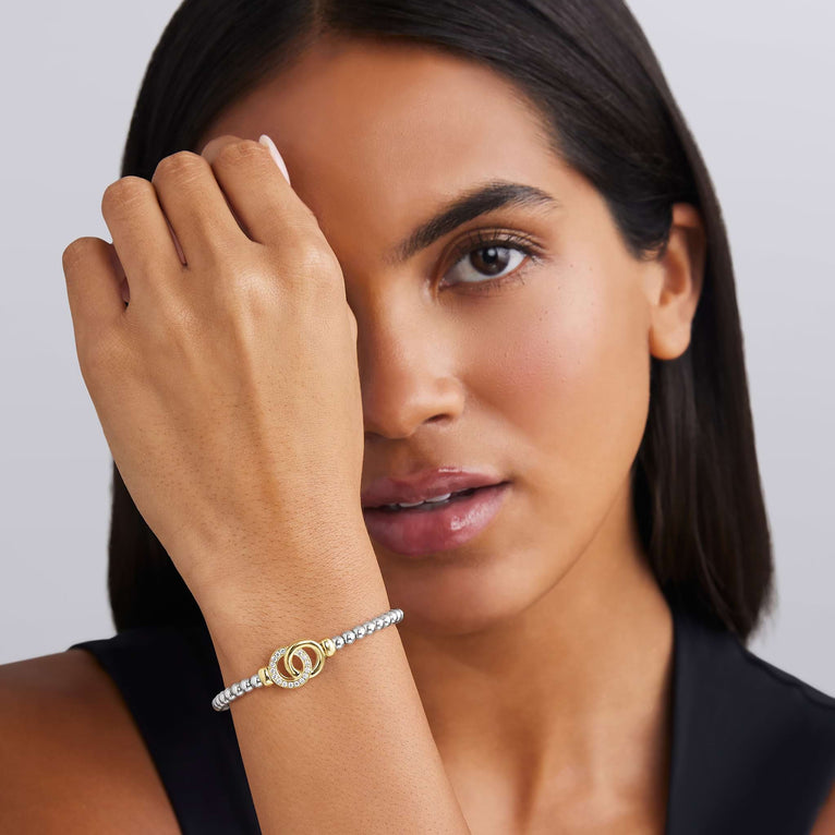 woman wearing everyday sterling silver beaded stretch bracelet with interlocking diamonds and gold details 