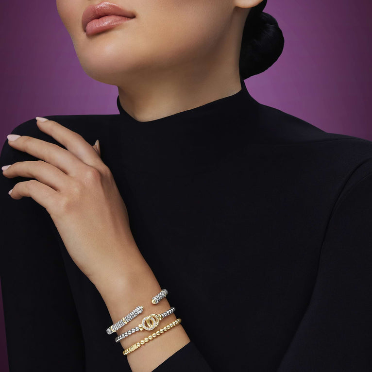 woman wearing three luxury sterling silver and gold bracelets styled with black blouse 