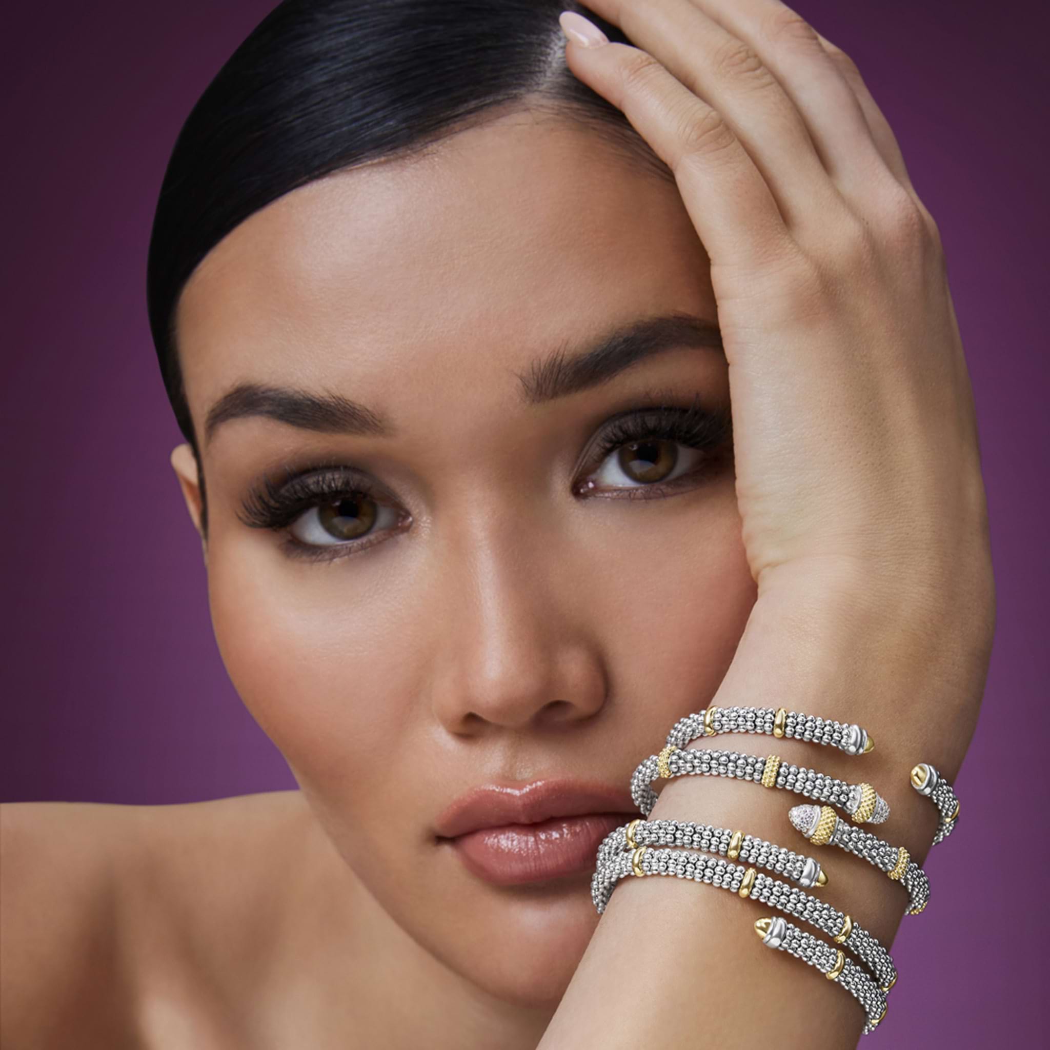 woman wearing three silver and gold bracelets on wrist
