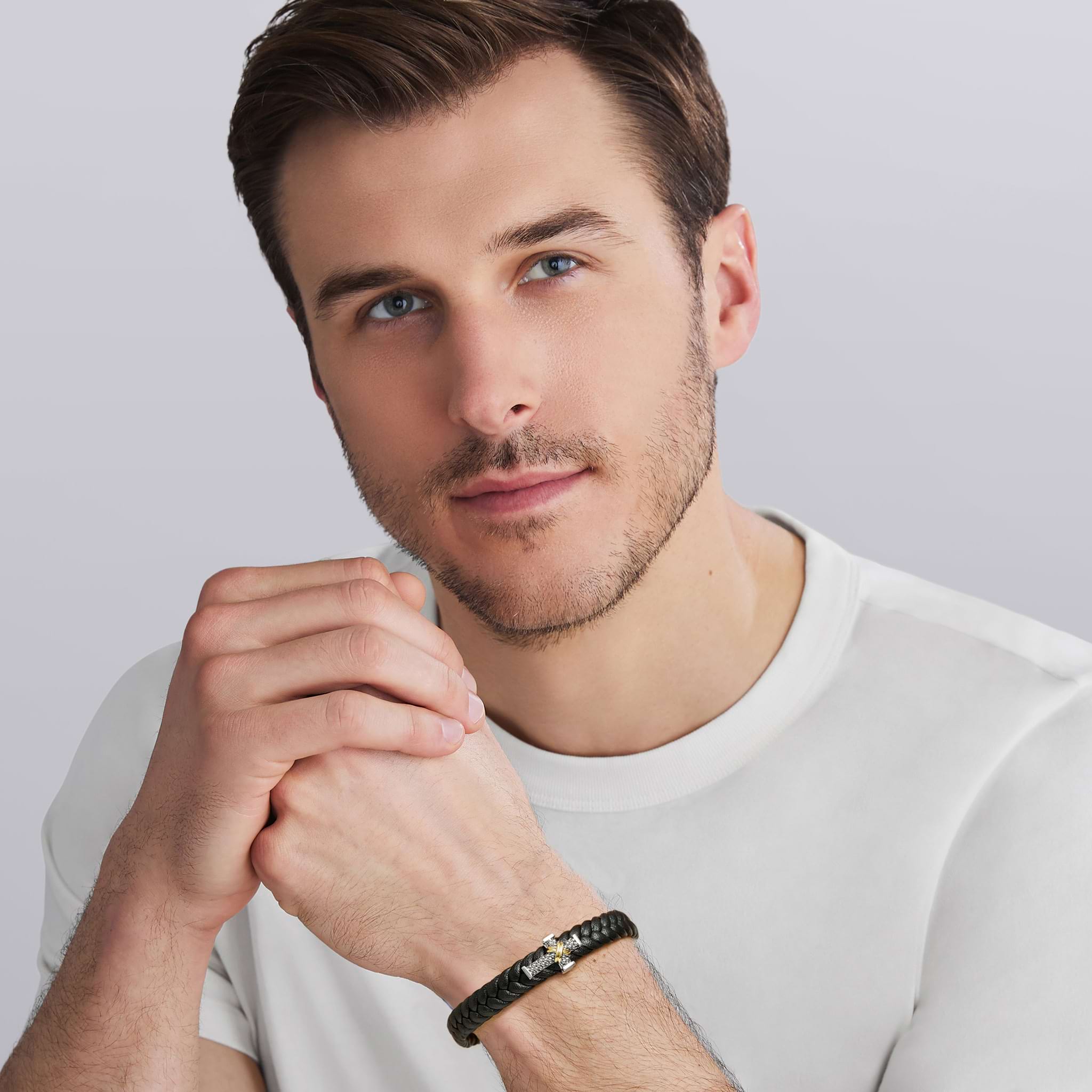 Man wearing the Anthem Two-Tone Braided Vegan Leather Cross Bracelet, showcasing black vegan leather with sterling silver and 18k gold accents for a refined, modern look.
