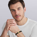 Young man wearing the Anthem Two-Tone Braided Vegan Leather X Bracelet, showcasing its black braided design and 18k gold accent for a modern, sophisticated look.
