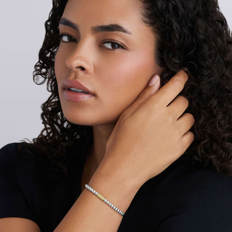 Woman wearing the Caviar Icon Two-Tone Caviar Icon Stretch Bracelet, featuring polished silver and gold beads, showcasing elegant LAGOS craftsmanship.