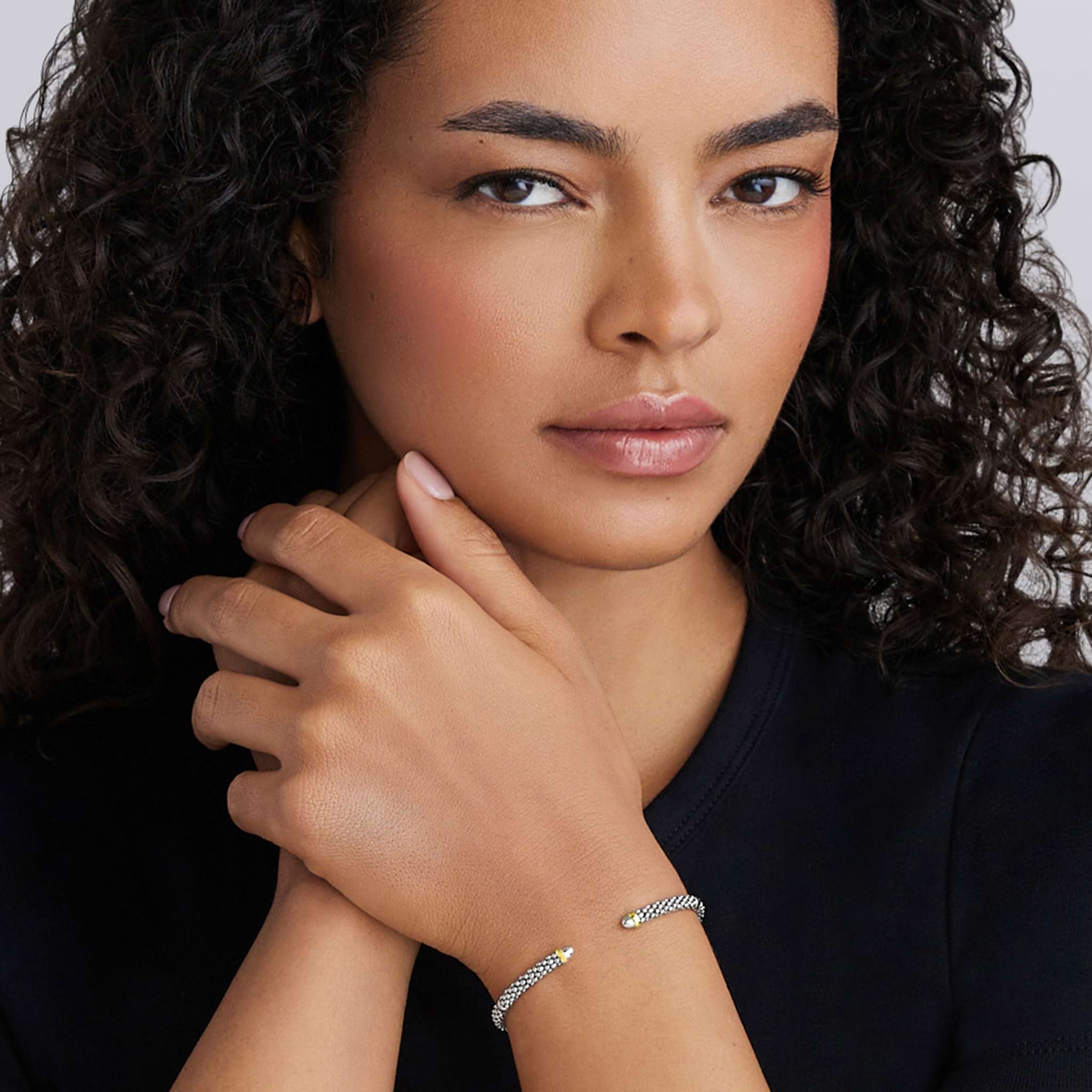 Young woman wearing the Signature Caviar Two-Tone Mini Versa Torque Bracelet in polished sterling silver with gold accents, featuring textured Caviar beading.
